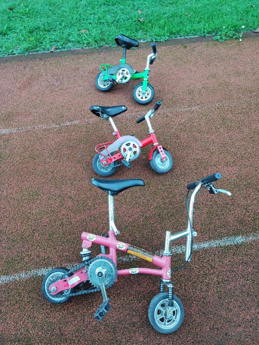 Drei Minibikes in Grün, Rot und Pink stehen hintereinander auf der Laufbahn.