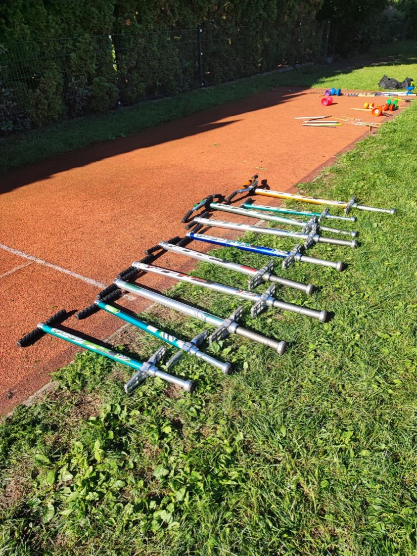 Rund ein Dutzend Pogo-Sticks liegen nebeneinander am Rand der Laufbahn.