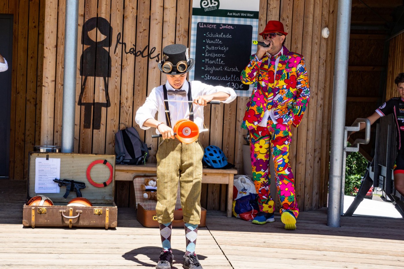 Show der Steampunk Jugglers bei den Wexl Trails: Lukas mit Diabolo, daneben Moderator Erwin „The Voice“ Pieler mit Mikrofon im bunten Blumenanzug.